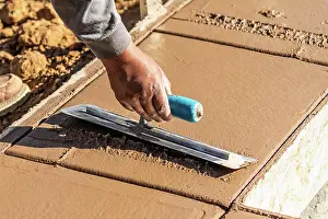 Construction Site Photos Drucke: Construction Worker Using Trowel On Wet Cement Forming Coping Around New Pool