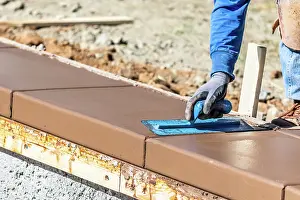 Building A New Pool Drucke: Construction Worker Using Trowel On Wet Cement Forming Coping Around New Pool