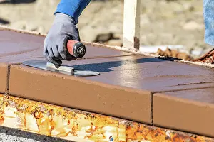 Contractor Services Offered Drucke: Construction Worker Using Trowel On Wet Cement Forming Coping Around New Pool