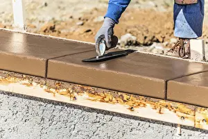 Swimming Pool Installation Drucke: Construction worker using trowel on wet cement forming coping around new pool