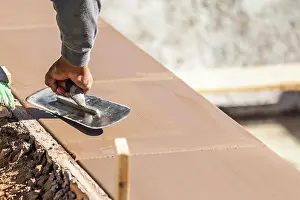 Building A New Pool Drucke: Construction Worker Using Trowel On Wet Cement Forming Coping Around New Pool