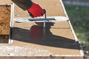Swimming Pool Building Drucke: Construction Worker Using Trowel On Wet Cement Forming Coping Around New Pool