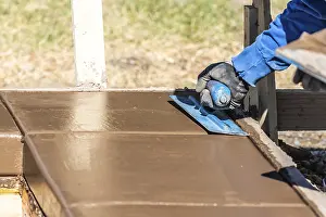 Swimming Pool Installation Drucke: Construction worker using trowel on wet cement forming coping around new pool