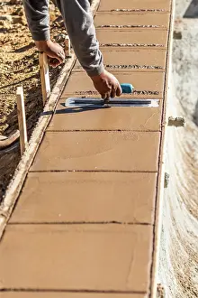 Cement Forming Techniques Drucke: Construction Worker Using Trowel On Wet Cement Forming Coping Around New Pool