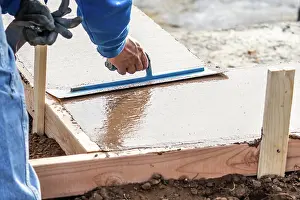 Cement Forming Techniques Drucke: Construction Worker Using Trowel On Wet Cement Forming Coping Around New Pool