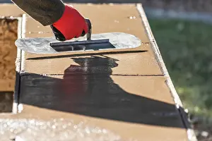Construction Site Photos Drucke: Construction Worker Using Trowel On Wet Cement Forming Coping Around New Pool