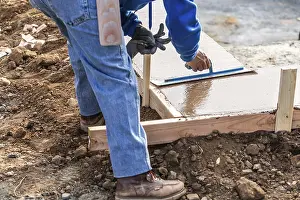 Construction Industry Workforce Drucke: Construction worker using trowel on wet cement forming coping around new pool
