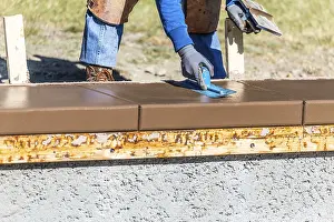 New Construction Site Drucke: Construction worker using trowel on wet cement forming coping around new pool