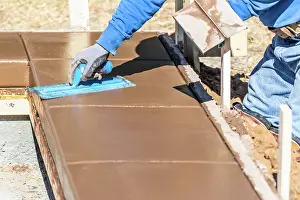 Swimming Pool Building Drucke: Construction Worker Using Trowel On Wet Cement Forming Coping Around New Pool