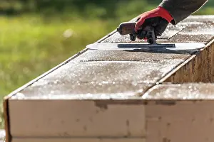 Construction Site Images Drucke: Construction Worker Using Trowel On Wet Cement Forming Coping Around New Pool