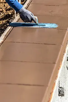 Contractor Services Offered Drucke: Construction Worker Using Trowel On Wet Cement Forming Coping Around New Pool