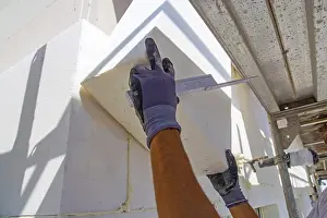 Energy Efficient Building Drucke: Construction workers insulate a house facade