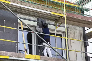 Energy Saving Construction Drucke: Construction workers insulate a house facade