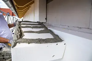 Residential Building Insulation Drucke: Construction workers insulate a house facade