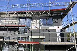 Energy Saving Construction Drucke: Construction workers insulate a house facade