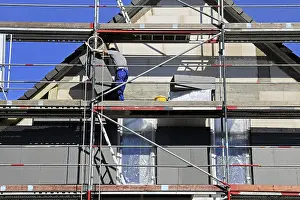 Energy Saving Construction Drucke: Construction workers insulate a house facade