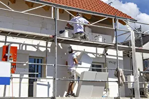 Energy Saving Construction Drucke: Construction workers insulate a house facade