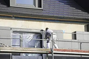 Construction Workman Drucke: Construction workers insulate a house facade