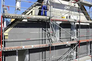 Energy Saving Construction Drucke: Construction workers insulate a house facade