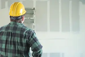 Hard Hat Safety Helmet Drucke: Contractor in hard hat looking at drywall