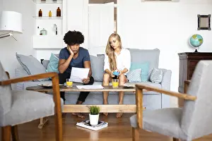 Modern Living Room Interior Design Drucke: A couple sits on a sofa analyzing financial documents and using a calculator