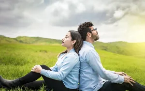 Bride And Groom Drucke: A couple sitting with their backs to each other on the grass