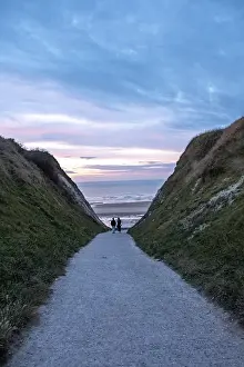 Deserted Evening Sky Drucke: A couple walks towards the beach at sunset