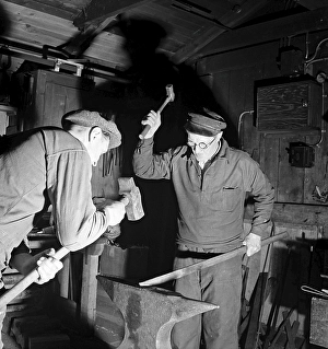 Handwerker der 1940er Jahre. Zwei Schmiede in einem Schmiedeofen, schlagen ein Stück Metall gegen den Amboss. Schweden 1947 Kristoffersson Ref AB6-3