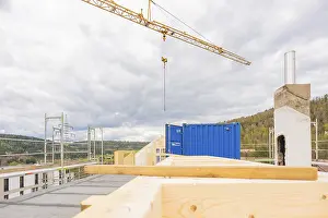 Blaukranich Drucke: Ein Kran auf einem Baustellen mit einem blauen Container und Holz.
