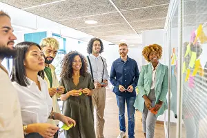 Communication In The Workplace Drucke: Creative process of young and multi-ethnic people using adhesive notes on a glass