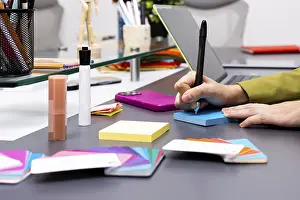 Colorful Interior Design Drucke: A creative workspace featuring hands writing on a blue notepad surrounded by colorful tools