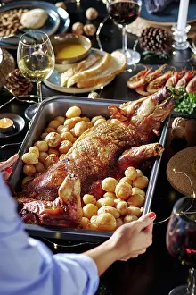 Candlelit Ambiance Drucke: Cropped unrecognizable woman's hands serving in a sumptuously set dining table featuring a roasted suckling pig