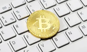Cryptocurrency Trading Platform Drucke: Cryptocurrency of the golden bitcoin lying over computer keyboard