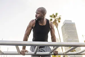 Outdoor Exercise Routine Drucke: A cuban man performs outdoor exercises on parallel bars