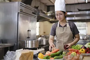 Meal Preparation Drucke: A culinary student stands in a professional training kitchen