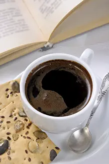 Deserted Table Setting Drucke: Cup of coffee and crackers on a table with an open book