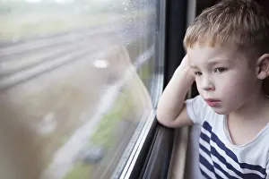Boy Looking Out Window Drucke: Curious boy looking out the window of a speeding train
