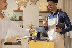 Contemporary Interior Design Drucke: A customer makes a payment using a card at a chic bag store