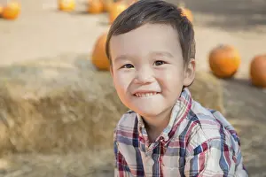 Autumnal Atmosphere Images Drucke: Cute mixed-race young boy having fun at the pumpkin patch