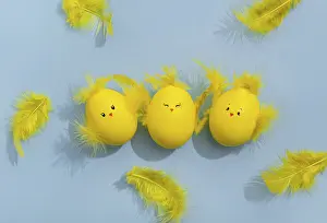 Colorful Easter Eggs Drucke: Cute yellow Easter eggs in the shape of chicks surrounded by feathers on a bright blue background