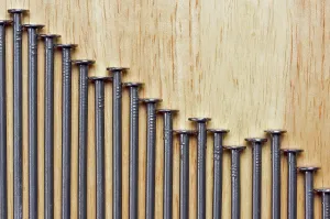 Construction Industry Supplies Drucke: Declining Graph of Nails on a Wood Background