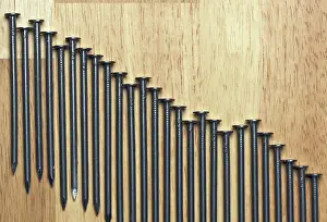 Close Up Construction Tools Drucke: Declining Graph of Nails on a Wood Background