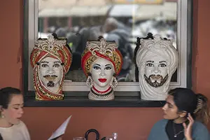 Drucke von In der Fensterfront eines indischen Restaurants in Portofino, Italien, präsentieren sich diese dekorativen Vasen mit Gesichtern indischer Motive Portofino Drucke: Indische Gesichter auf Dekorationsvasen in einem indischen Restaurant in Portofino