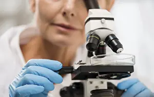 Female Scientist Microscope Drucke: Defocused female scientist looking through microscope