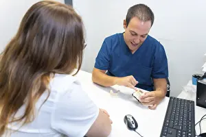 Healthcare Professional Advice Drucke: Dental clinic, dentist explaining to a client the teeth to be implanted in a model