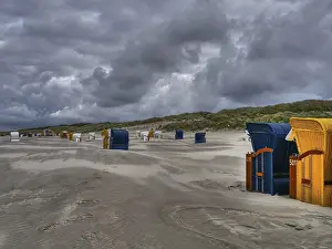 Uninhabited Coastal Landscape Drucke: Deserted beach with many beach chairs under a dramatically cloudy sky