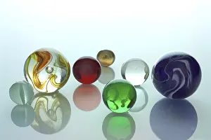Studio Shot Glass Drucke: Several differently colored marbles on a mirror surface