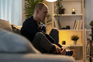 Young Adult With Physical Disability Drucke: Disabled man sitting alone in the sofa with sad expression in the night