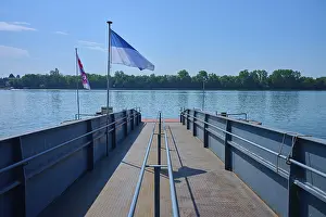Rhine River Germany Drucke: Dock on the river, flags fly in the wind under a clear sky