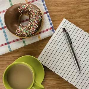 Breakfast Table Setup Drucke: Doughnut coffee and notepad with pen on a table